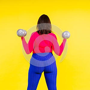 Young smiling happy chubby overweight plus size big fat fit woman warm up training hold dumbbells