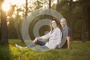 Young smiling happy couple, sitting in grass field,