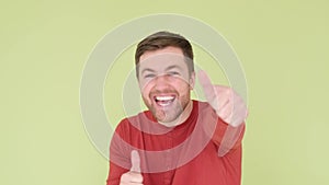 Young smiling happy man showing thumbs up gesture isolated on light olive background studio portrait.