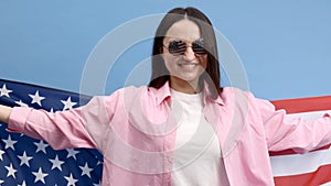 Young smiling happy woman wears casual clothes holding American flag and looking to the camera