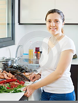 Young smiling housewife with raw seafood