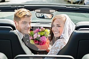 Just Married Couple With Bouquet In The Car