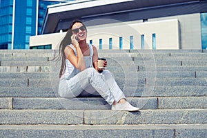 Young smiling lady with a cup of â€œcoffee to goâ€ talking on