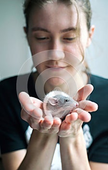 Young smiling lady with little baby rat in her palms