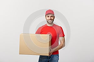 Young smiling logistic delivery man in red uniform holding the box on white background