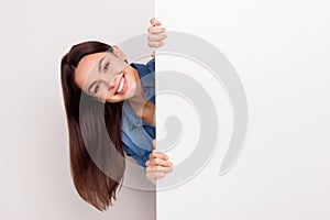 Young smiling long-haired girl standing and appear near big poster, place for copy space