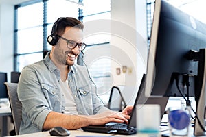 Young smiling male call center operator doing his job with a headset.Portrait of call center worker at office.