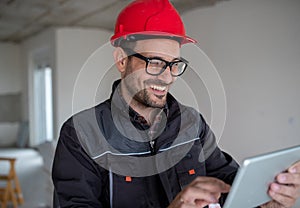 Male engineer with helmet using tablet in factory