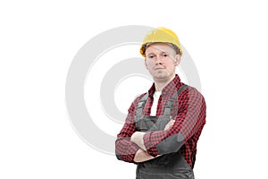 Young smiling male worker in a construction worker, in a yellow helmet, working overalls and a red checkered shirt on a