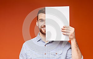 Young smiling man covering half of his face beside white sheet