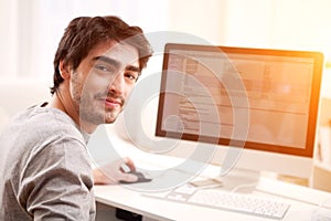 Young smiling man in front of computer