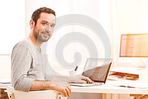 Young smiling man in front of a computer
