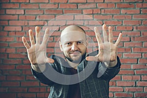 Young smiling man with hands in air to say stop or hypnotist gesture