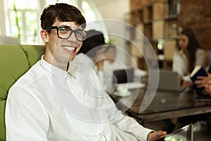 Young smiling man in official clothes and glasses, working at stylish modern office
