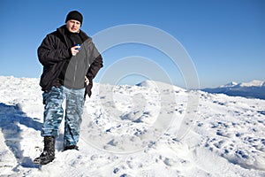Young smiling man photographer in winter clothing drinking tea from thermos