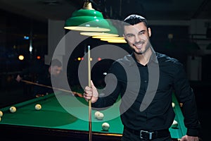 Young smiling man playing billiard game