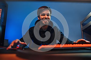 Young smiling man playing video computer games at home