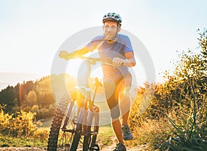 Young smiling man pushing a mountain bike up the hill. Active adventure travel on bicycle