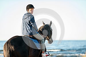 Young smiling man riding horseback at wavy sea background