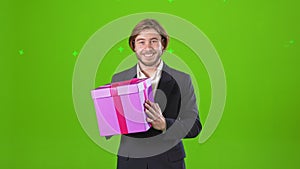 Young, smiling man standing in studio, holding present, gift box.