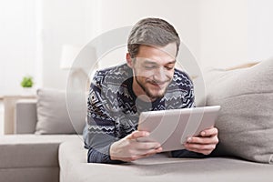 Young smiling man with a tablet computer in hand at home.