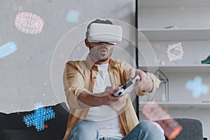 Young smiling man in VR glasses playing game using joystick, augmented reality