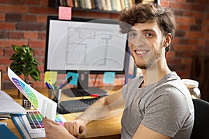 Young smiling man working at his workplace