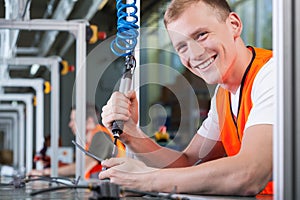 Young smiling man working on the production line