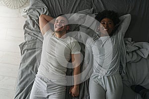 Young smiling mixed race couple lying together in bed