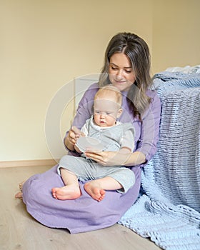 Young smiling mom playing with son baby boy in kids room