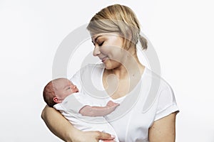 A young smiling mother holds a newborn baby in her arms. Love and tenderness. White background. Space for text