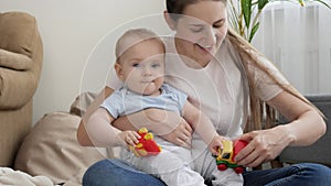 Young smiling mother playing with her baby son in toy cars at home. Concept of family having time together and children