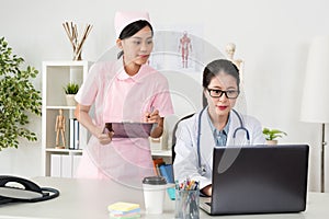 Young smiling nurse using clipboard writing note