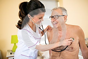 Young smiling positive doctor examining senior patient with stet