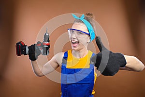 Young smiling practical woman working with screwdriver showing thumbs up gesture. Portrait of a builder or handyman with