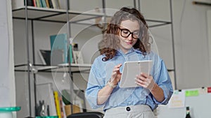 Young smiling professional business woman using digital tablet in office.