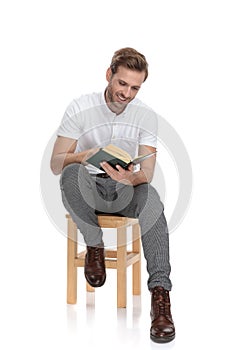 Young smiling seated man read a book