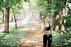 Young smiling sporty woman running in park. Fitness girl jogging in park