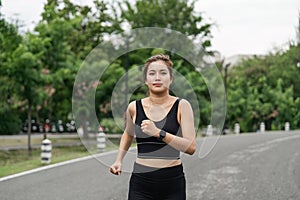 Young smiling sporty woman running in park in the morning. Fitness girl jogging in park