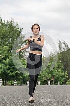 Young smiling sporty woman running in park in the morning. Fitness girl jogging in park