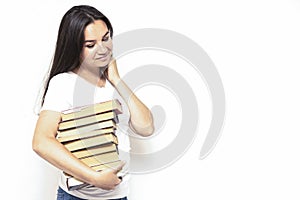 Young smiling student woman in white t-shirt holding textbooks and books in a pile on a white backdrop. College