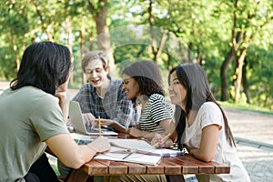 Young smiling students sitting and studying outdoors