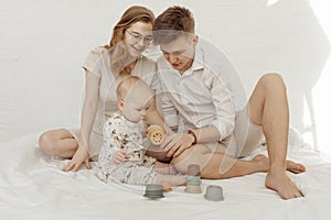 Young smiling stunning family with cherubic infant baby playing with modern pastel colorful silicone bowls