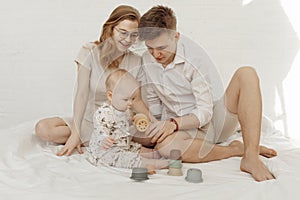 Young smiling stunning family with cherubic infant baby playing with modern pastel colorful silicone bowls photo