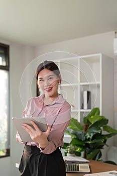 Young smiling successful employee business woman work use hold tablet stand at workplace desk at home office