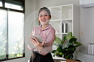 Young smiling successful employee business woman work use hold tablet stand at workplace desk at home office