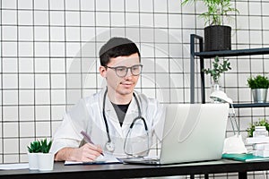 Young and smiling therapist in uniform filling up documents