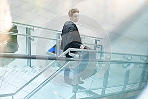 Young smiling traveling businessman on a stairway