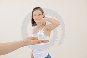 Young smiling woman advertising remedy for male potency close up, white blurred background. Holding in hand and pointing
