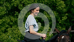 Young smiling woman in blue shirt riding a horse